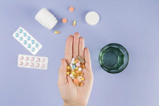 Hand holding various prescription pills and capsules