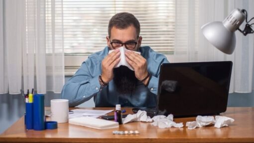 Unwell office worker displaying cold and flu symptoms during work hours